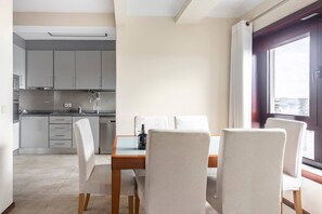 Una cocina moderna con armarios grises, una mesa de comedor de madera y sillas blancas.