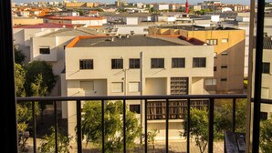 Un balcon donnant sur un quartier résidentiel, avec des bâtiments aux toits plats et un ciel dégagé.