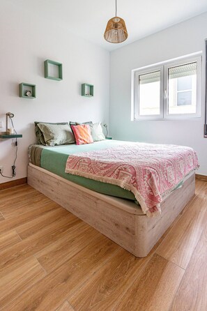 Ein Schlafzimmer mit einem hölzernen Bett, einer grünen Wand und einem Fenster.