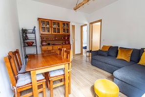 Ein modernes Wohnzimmer mit einem dunkelgrauen Sofa, einem Holzesstisch und einem gelben Ottomanen.