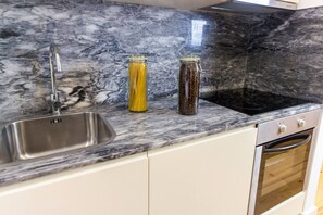 A kitchen with a marble countertop, stainless steel sink, and an oven. - Guest H4U - Porto Fontainhas Romantic Place (Porto)