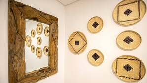 Una pared con un marco de madera rústico que contiene un espejo y varias cestas tejidas con diseños geométricos.