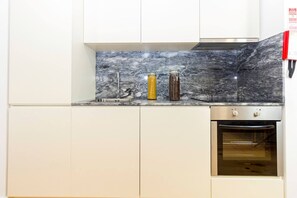 A kitchen with white cabinets, a marble backsplash, and a built-in oven. - Guest H4U - Porto Fontainhas Romantic Place (Porto)