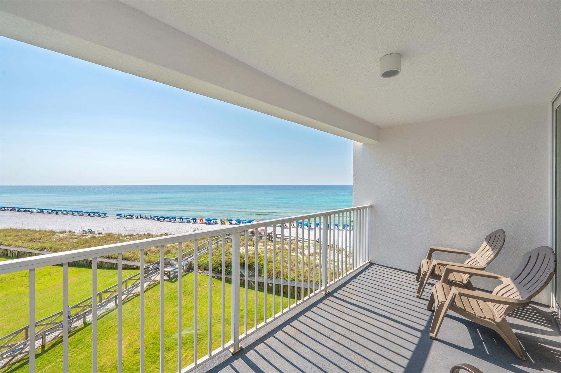 A balcony with a view of the beach and ocean.