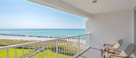 A balcony with a view of the beach and ocean.