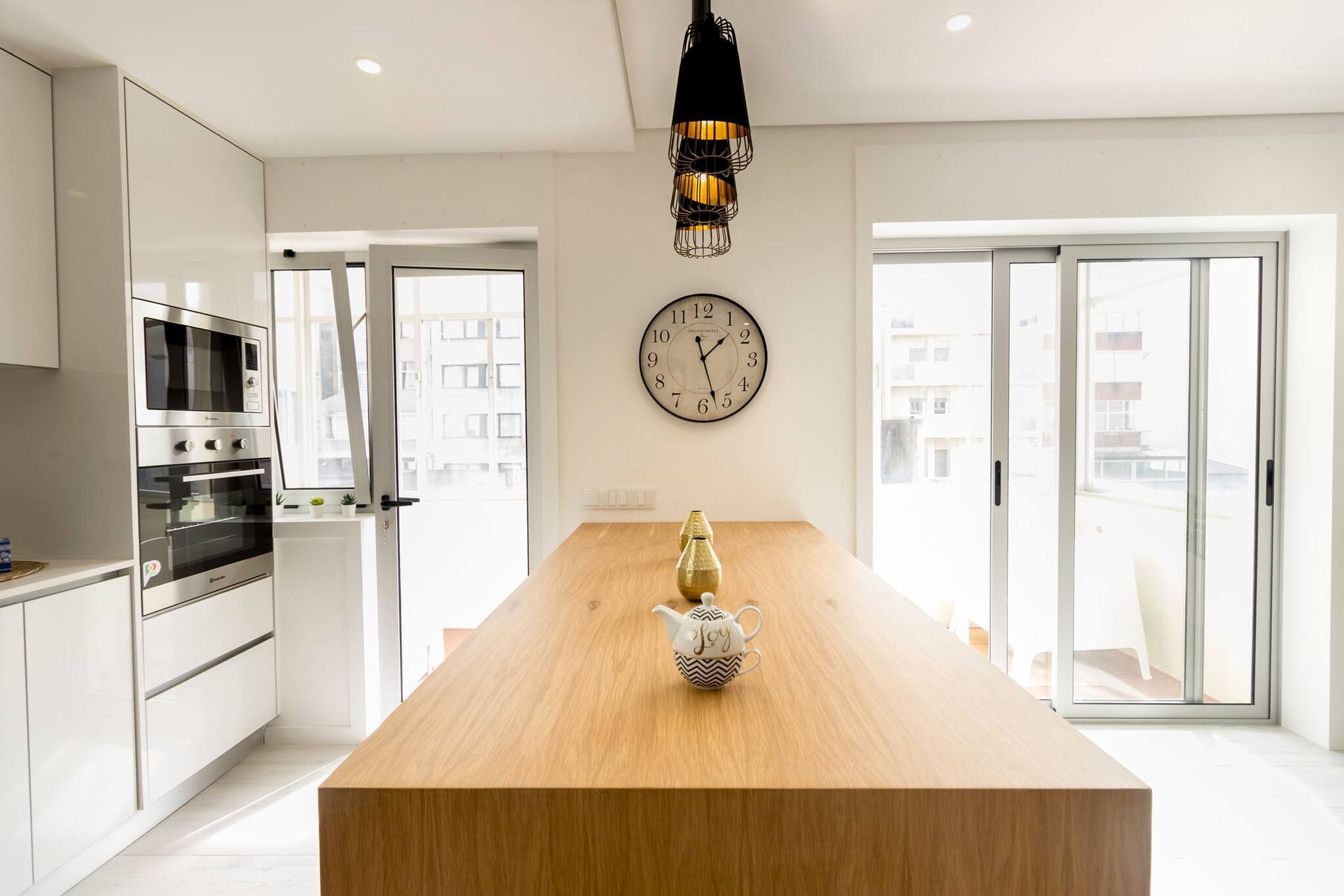 A modern kitchen with a wooden island, stainless steel appliances, and a wall clock.
