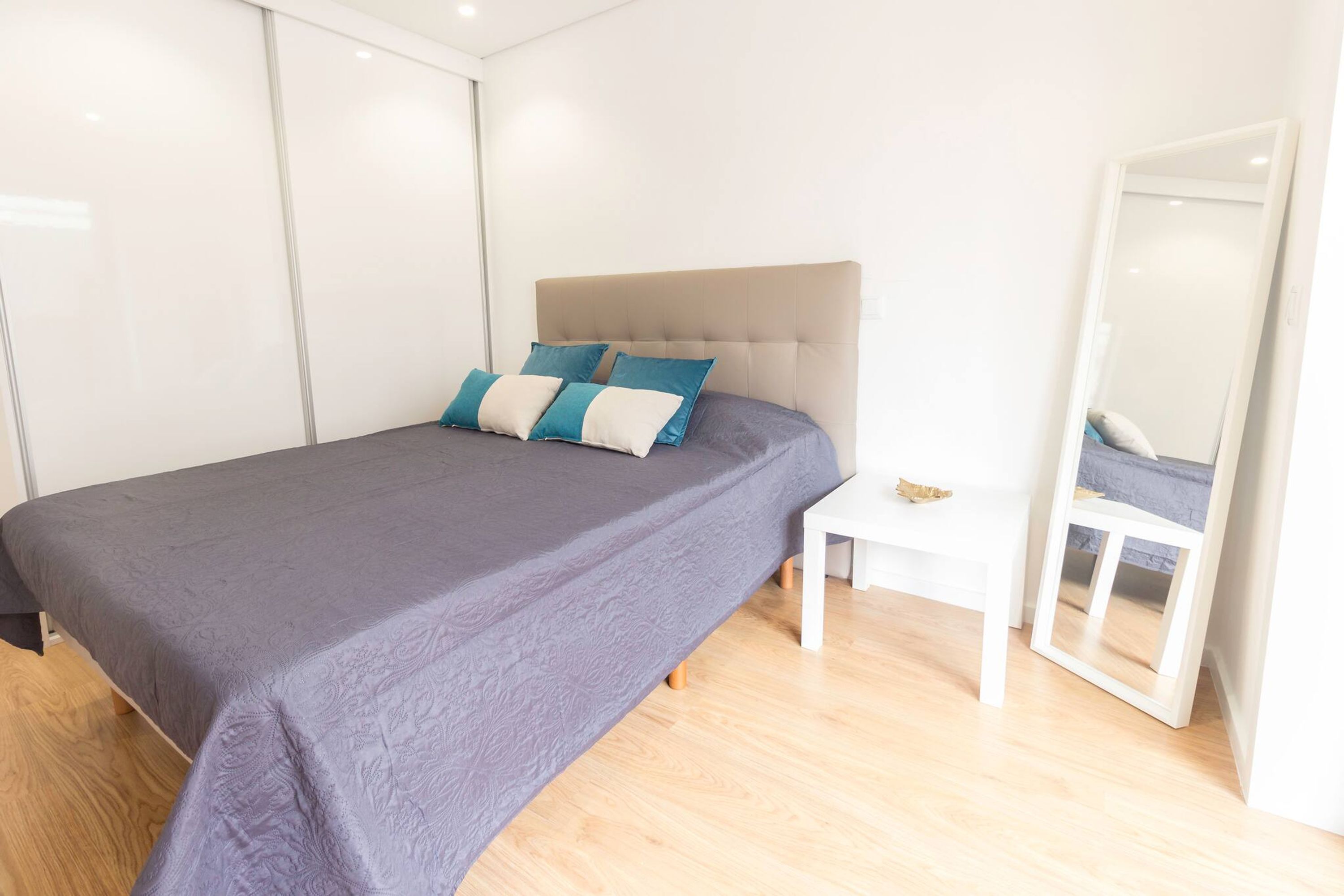 Un dormitorio moderno con una cama grande, una mesita de noche y un espejo.