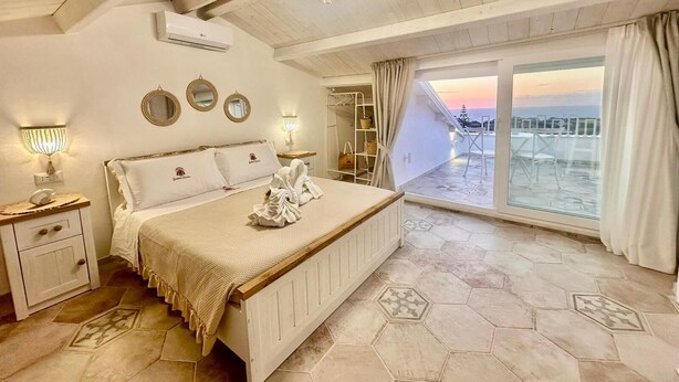 A bedroom with a large bed, a balcony with a view, and a chandelier. - Godano Rooms (Drapia)