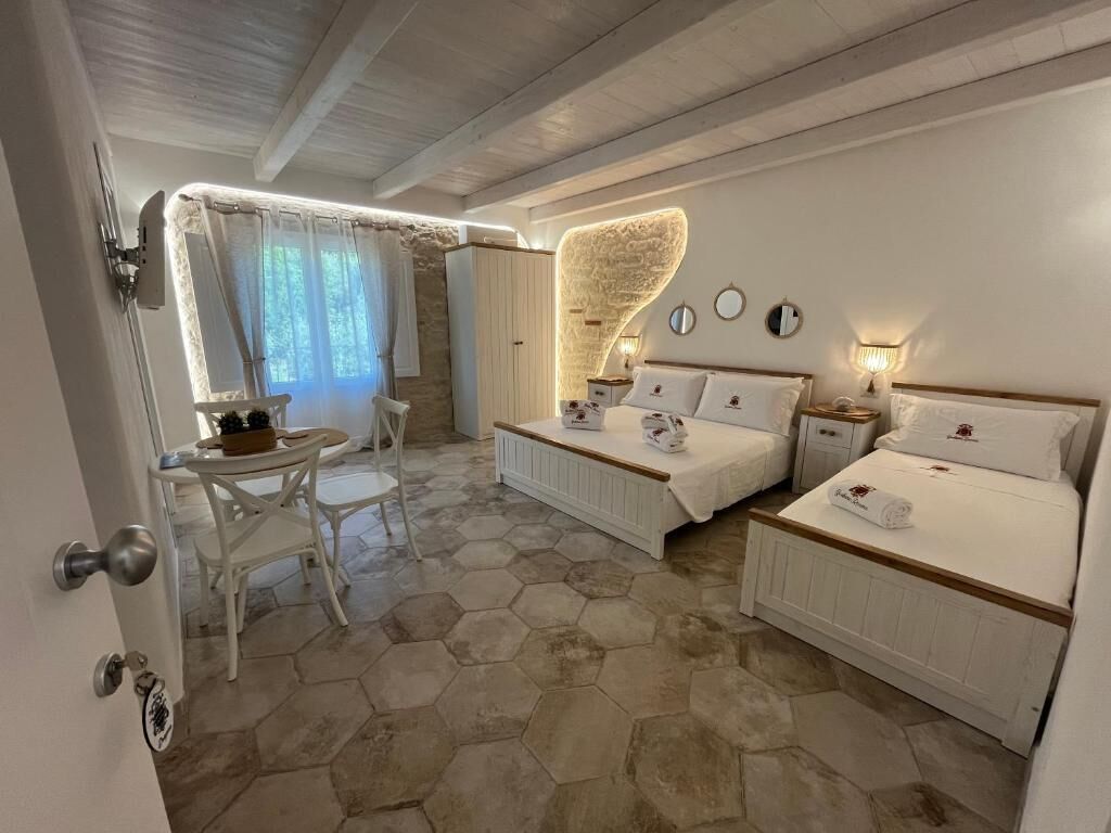 A bedroom with two beds, a dining area with a table and chairs, and a bathroom with a shower.