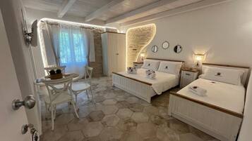 A bedroom with two beds, a dining area with a table and chairs, and a bathroom with a shower.