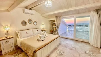 Quarto de hotel com uma cama grande, varanda e vista, e um candelabro.