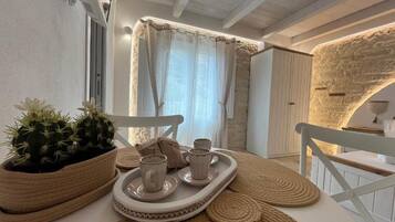 A cozy dining area with a table set for two, featuring woven placemats and a tray with cups and saucers.