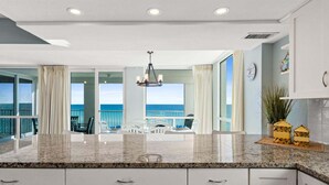 Una cocina moderna con una isla grande, armarios blancos y vistas al océano.