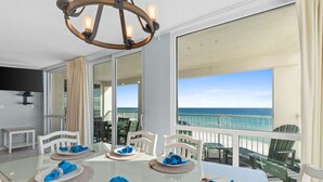 Comedor con mesa lista para cuatro personas, con vista a la playa.