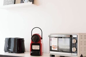 A kitchen counter with a toaster, a portable electric kettle, and a microwave oven. - Rome Cinecittà Suite - Apartment near Metro A Subaugusta (Roma)