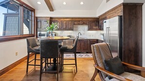 A modern kitchen with dark wood cabinets, a stainless steel refrigerator, and a dining area with a round table and chairs.