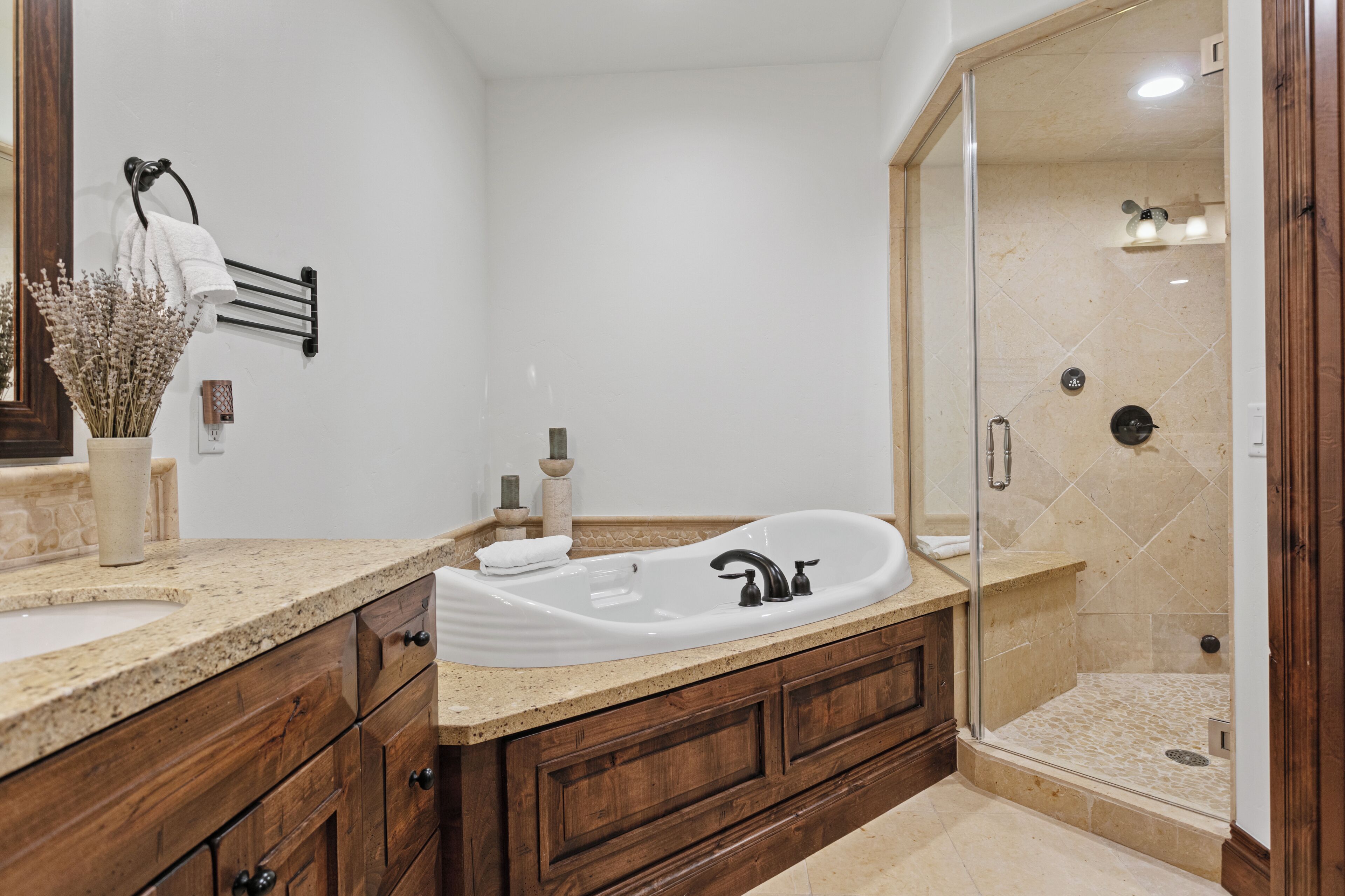 A bathroom with a freestanding bathtub, a glass-enclosed shower, and wooden cabinetry.