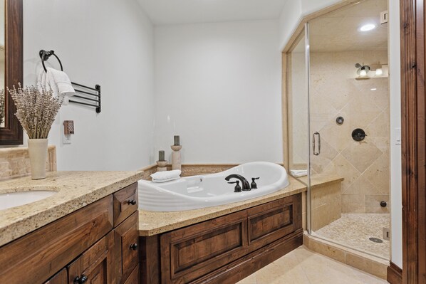 A bathroom with a freestanding bathtub, a glass-enclosed shower, and wooden cabinetry.