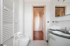 Un baño moderno con inodoro, zona de ducha y lavabo.