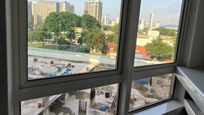 Aussicht aus einem Fenster bei blauem Himmel, zeigt eine Stadtansicht mit verschiedenen Gebäuden und einer Baustelle darunter.