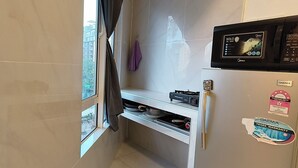 Eine kleine Küche mit einer eingebauten Mikrowelle, einem Gasherd und einem Kühlschrank.