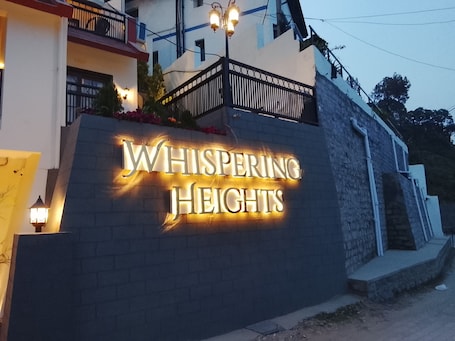 A building with a sign that reads 'Whispering Heights.'. whispering heights