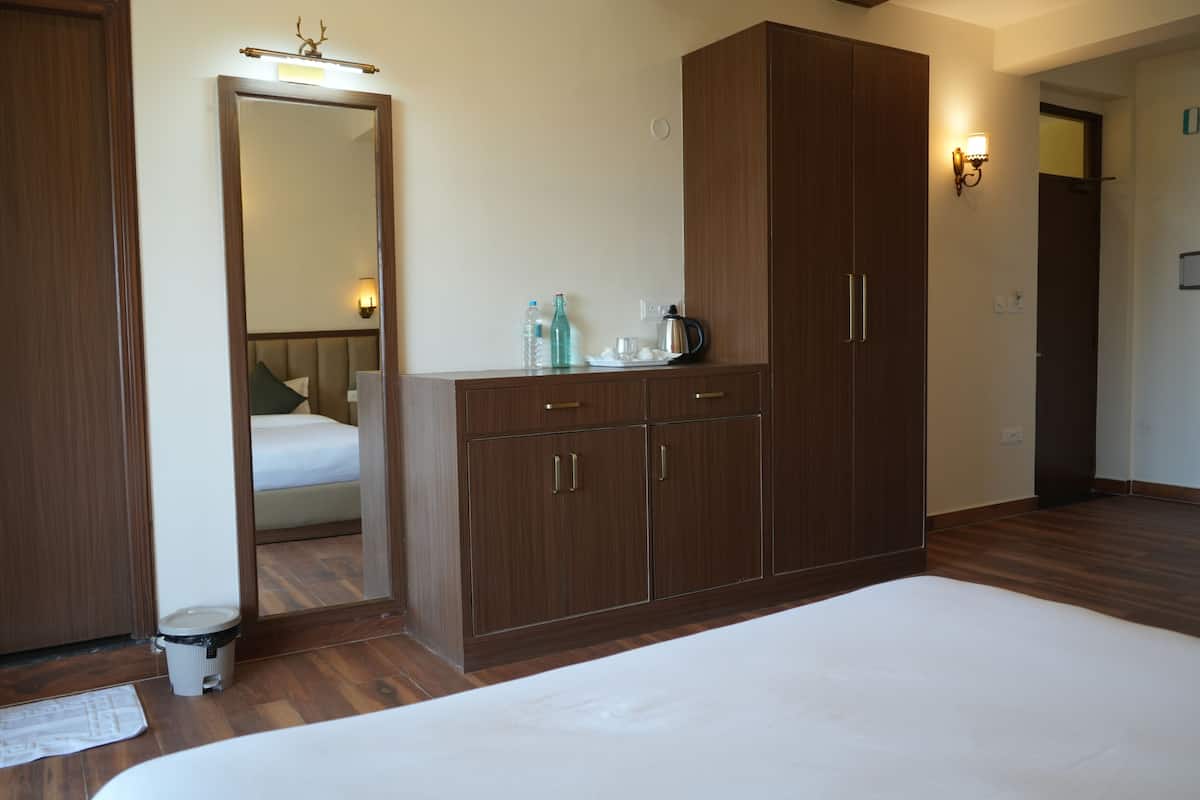 A bedroom with a large bed, wooden wardrobe, and a mirror.