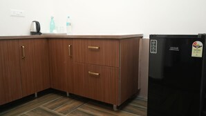 Eine Küche mit Holzschränken, einem schwarzen Kühlschrank und einer Arbeitsplatte mit Wasserkocher und Wasserflaschen.