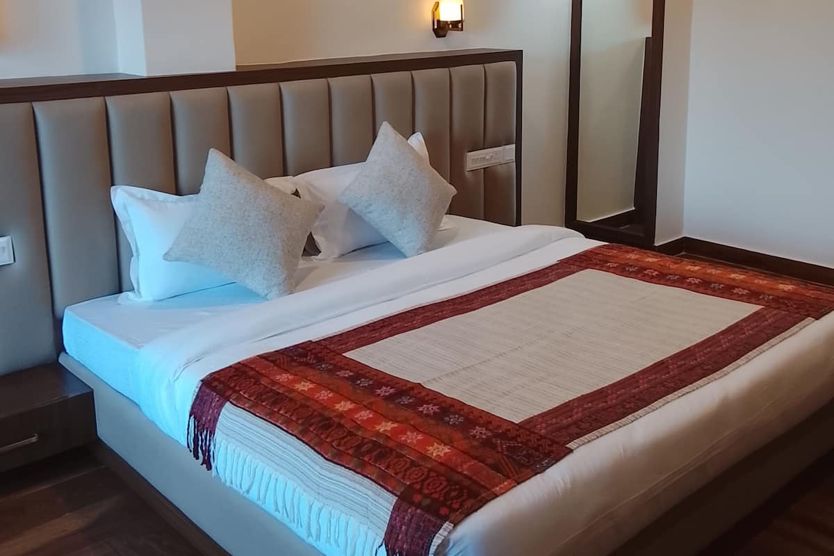 A neatly made bed with a red and white blanket, a wooden headboard, and two wall-mounted lamps.