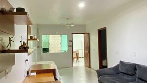 A spacious living room with a grey sofa, a wooden coffee table, and a dining area with a table and chairs. - Casa Aconchego Barra Velha - SC (Barra Velha)