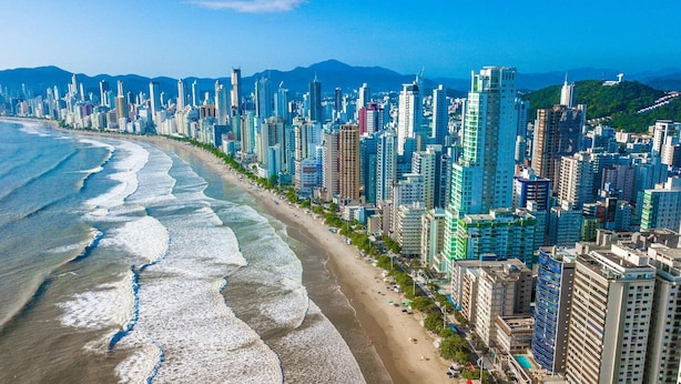 A coastal cityscape with high-rise buildings, a beach, and mountains in the background. - Casa Aconchego Barra Velha - SC (Barra Velha)