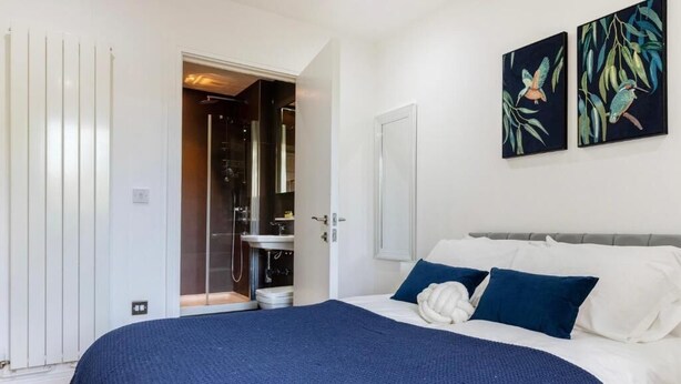A bedroom with a bed, a white door, and two wall-mounted paintings. - Stunning Studio Flat Minutes From Lewisham Station With View (London)