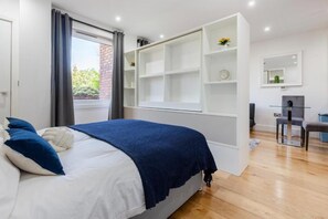 A bedroom with a bed, a built-in wardrobe, a desk, and a chair. - Stunning Studio Flat Minutes From Lewisham Station With View (London)