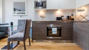 A modern kitchen with a built-in microwave, oven, and coffee maker. - Stunning Studio Flat Minutes From Lewisham Station With View (London)