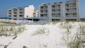 Un hôtel situé en bord de mer, doté de nombreux balcons, d’une piscine et de parasols de plage.