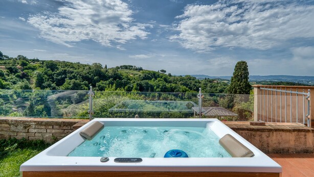 Un bain à remous offrant une vue dégagée sur un paysage luxuriant et des collines lointaines.