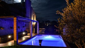 Une piscine avec une structure en briques et un espace détente abrité.
