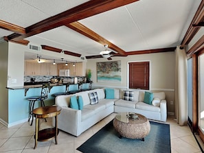 A spacious living area with a white sofa, a coffee table, and a kitchen in the background. - Ocean Breeze West #801 | Gulf-Front, Corner Balcony + Resort Amenities (Perdido Key)