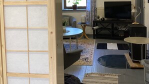 Una sala de estar con televisor, sofá, mesa de centro y una ventana con cortinas.