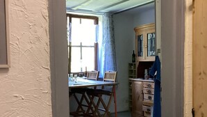 Una habitación con una mesa de comedor, sillas, un armario y una alfombra estampada.