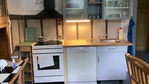 Una cocina compacta equipada con estufa, horno, lavavajillas y armarios.