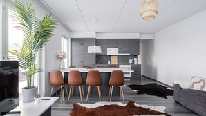 Una sala de estar moderna con un tapiz grande de cuero de vaca marrón y blanco, un sofá gris y un comedor con una mesa blanca y sillas marrones.