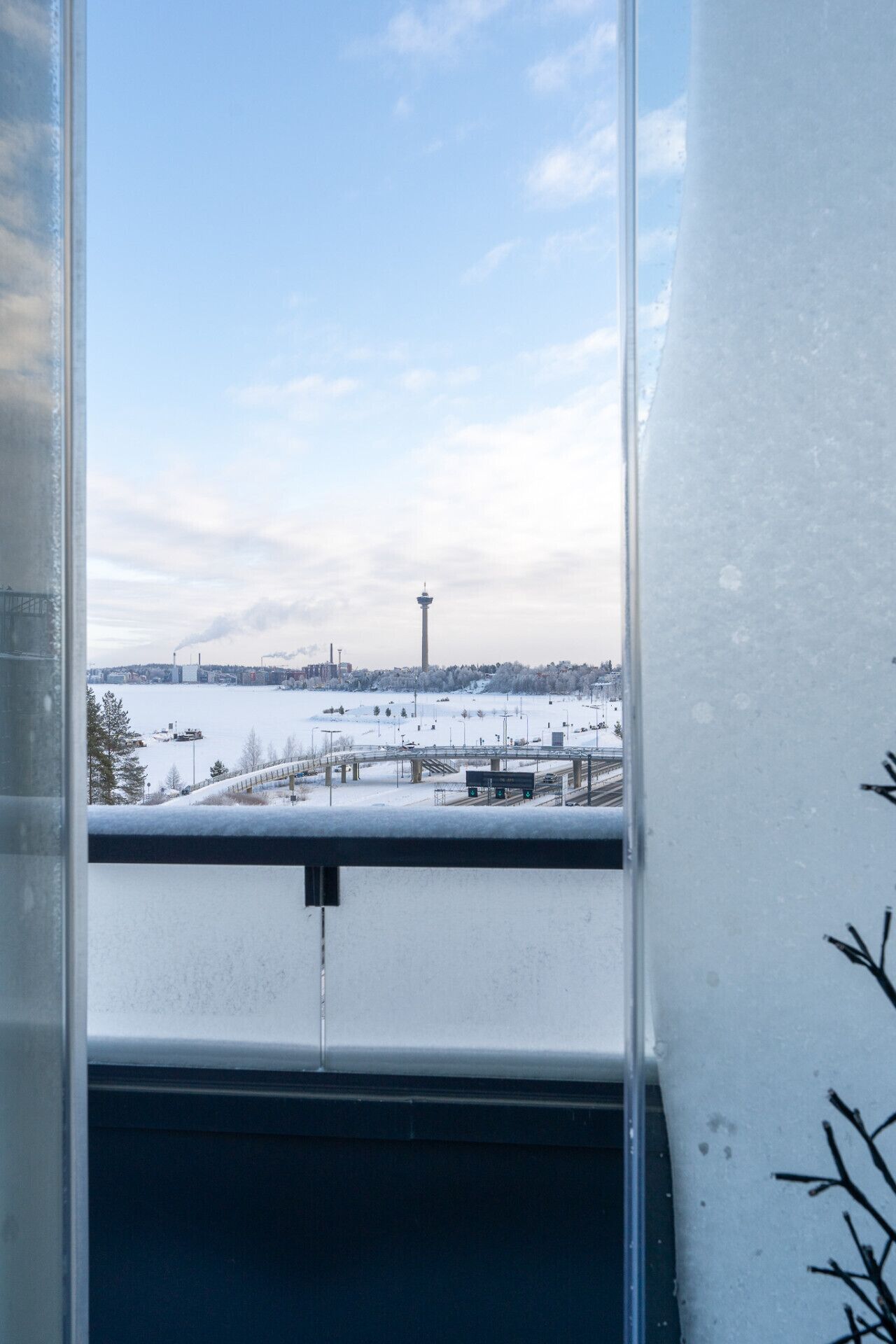 A view from a window with a snowy landscape, including a tower and industrial buildings.