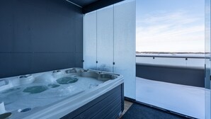 Un jacuzzi moderno en el interior con vista a un horizonte urbano a través de un amplio ventanal.