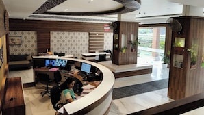 Un espace d’accueil doté d’un bureau incurvé, de plusieurs écrans d’ordinateur et d’un coin salon avec un canapé et des fauteuils.