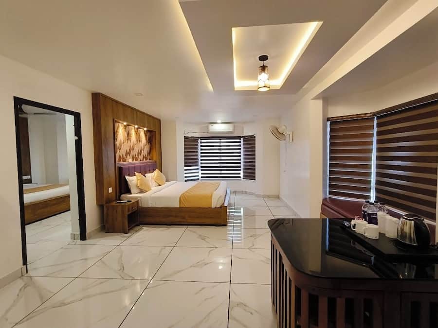 A modern hotel room with a bed, a seating area, and a kitchenette.