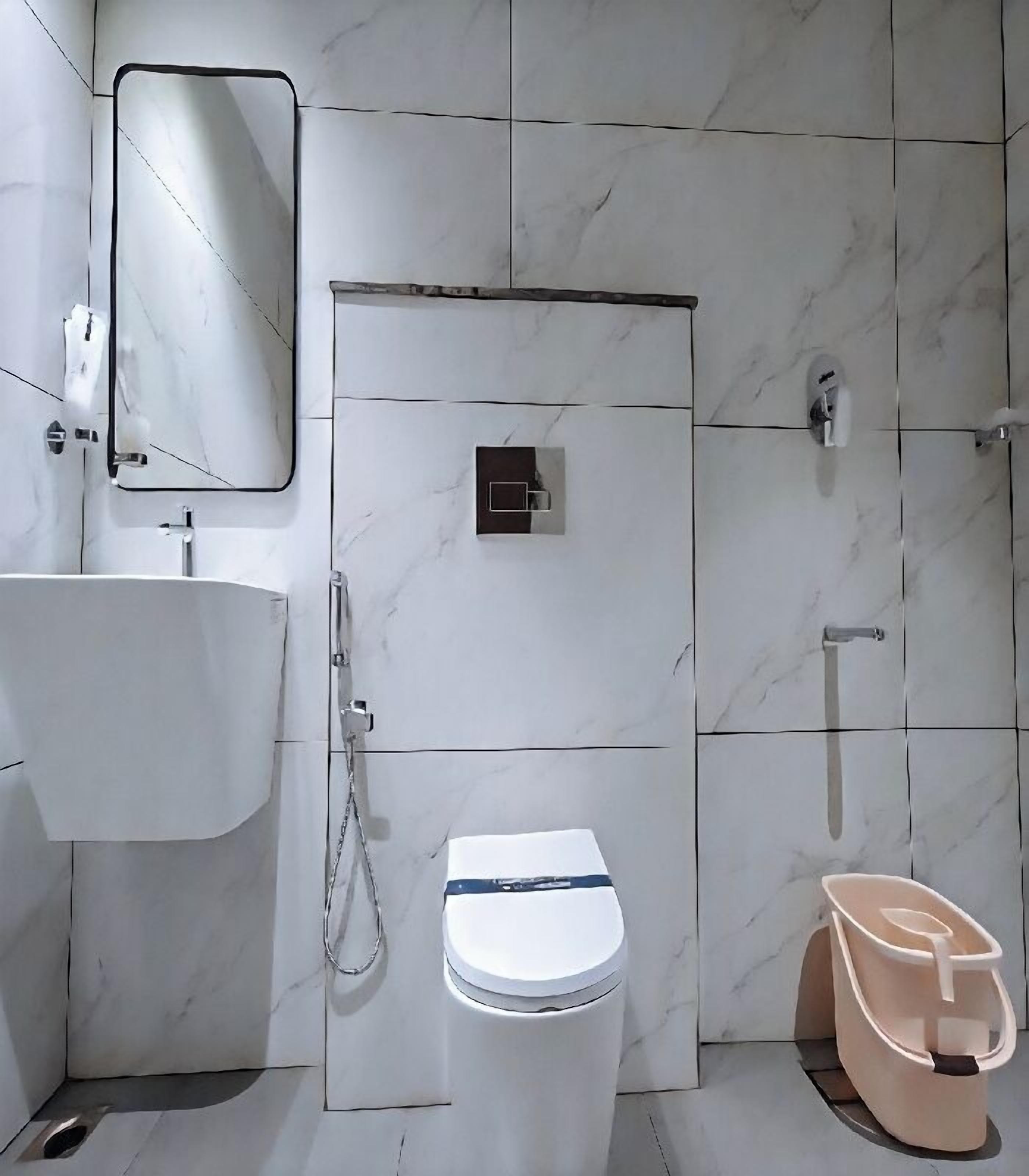 Une salle de bain avec des toilettes blanches, un lavabo, un miroir et une douche.
