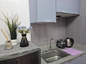Eine moderne Küche mit einer Granitabdeckung, einer Edelstahlspüle und einem Wasserkocher. Auf der Arbeitsplatte befinden sich Topfpflanzen und eine Vase mit Blumen.