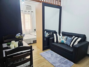 Ein gemütlicher Wohnraum mit einer Couch, einem kleinen Tisch mit Kerzen und einem Sessel.