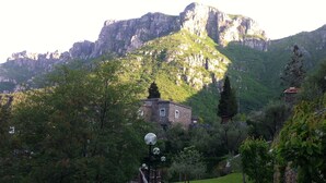 Un paysage montagneux avec un bâtiment en pierre, entouré d’une végétation luxuriante.